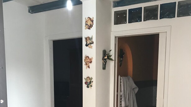 Un pasillo con piso de madera, un tapete azul y un armario con ropa colgada y una cesta.