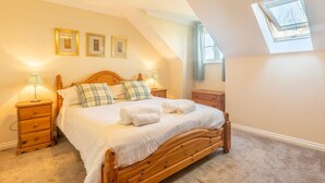 Un dormitorio con una cama de madera, dos mesitas de noche y un tragaluz.