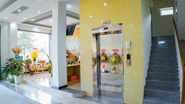 Eine Hotelhalle mit einer Rezeption, einer Treppe und einem Schild mit der Wegbeschreibung.