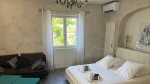 Un dormitorio con cama, sofá, mesa y ventana con cortinas.