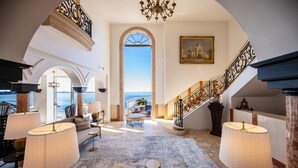 Un hall d’entrée spacieux offrant une vue sur la mer, un magnifique escalier et un mobilier élégant.