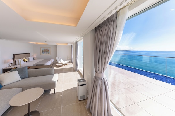 Una habitación de hotel moderna con un balcón grande, un sofá, una mesita y una cama.