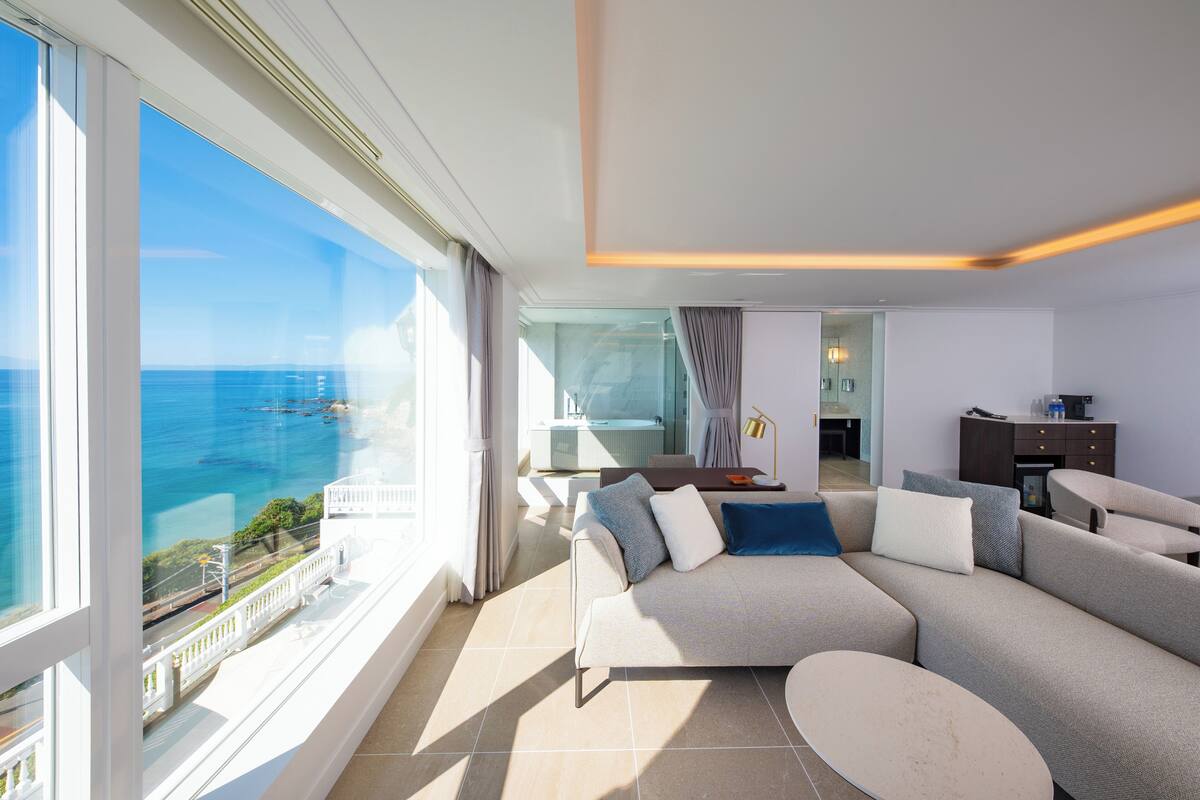 Ein modernes Wohnzimmer mit einem großen Fenster und Meerblick.