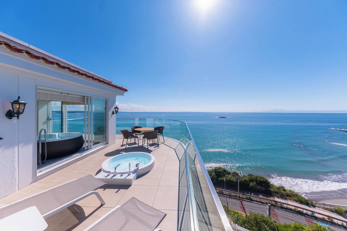 Ein Balkon mit Pool, Sitzgelegenheit und Blick aufs Meer.