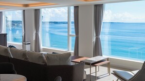 Une chambre moderne dotée d’une grande fenêtre donnant sur la mer. On y trouve un canapé, une petite table et une chaise.