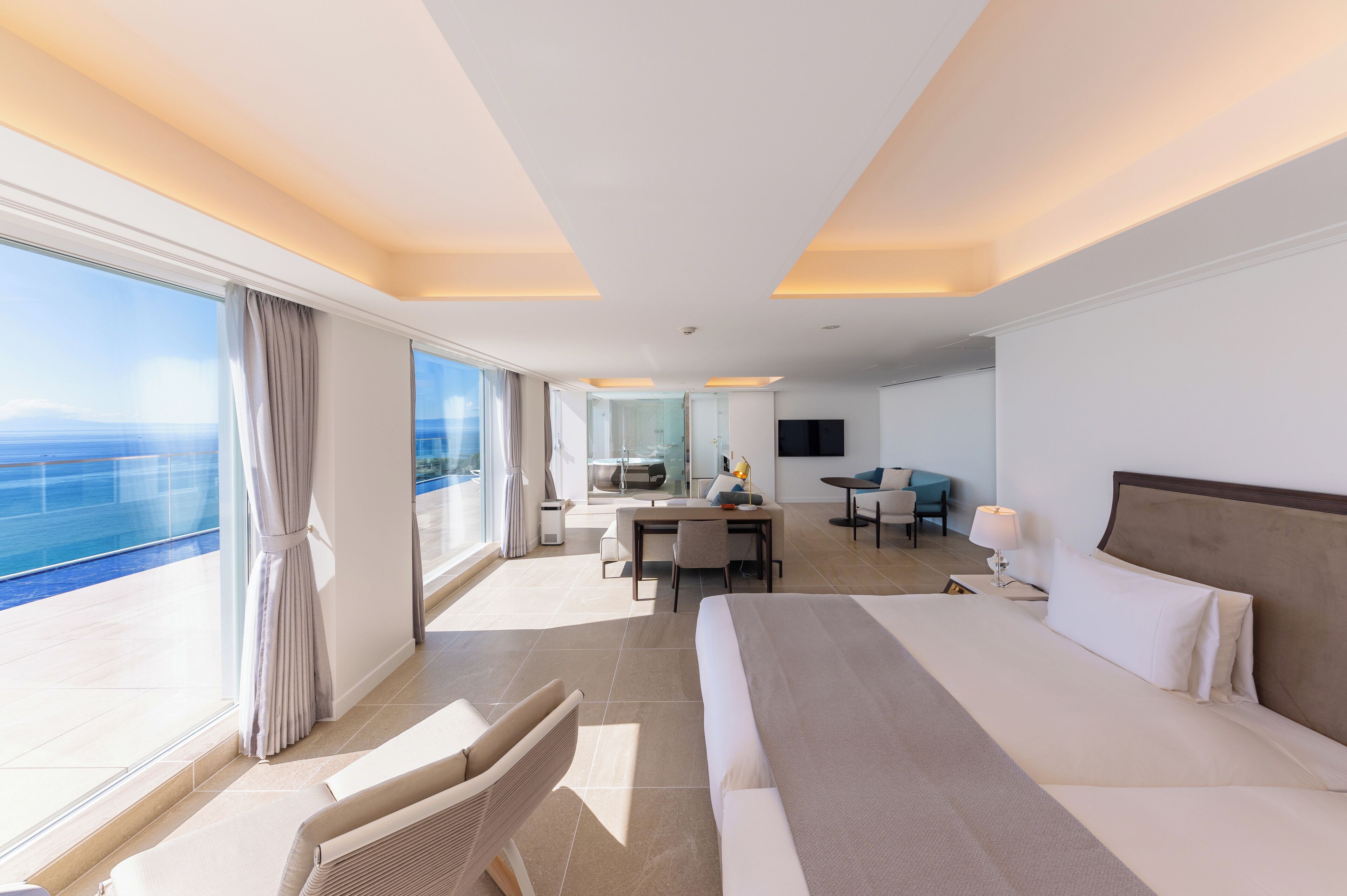 Une chambre d’hôtel moderne avec un grand lit, un bureau et une vue sur l’océan.