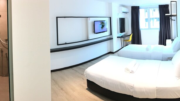 A hotel room with a shower, toilet, bed, TV, and a desk with a chair.
