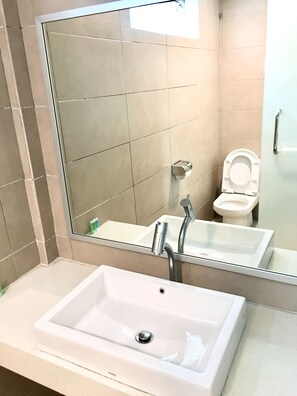 A bathroom with a white sink, a mirror, and a toilet.