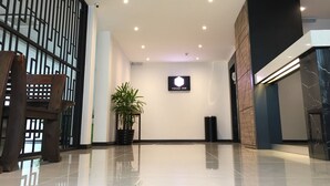 Un moderno vestíbulo de hotel con piso pulido, una planta en maceta, un cartel de Texas Inn y una cámara de seguridad.
