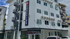 Un edificio de varios pisos con un letrero que dice "Texas Inn" y un cartel que indica "Apertura Suave".