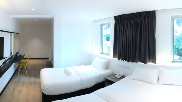 Una habitación de hotel moderna con un espejo grande, un sofá blanco, una mesita de noche con un teléfono y una ventana con cortinas.