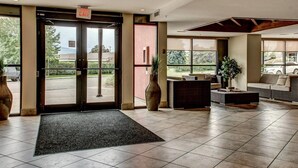 A hotel lobby with a reception desk, seating area, and large windows offering a view of the outdoors. - Playa Del Sol Retreat 550 | Pool + Hot Tub | Sleeps 6 (Kelowna)