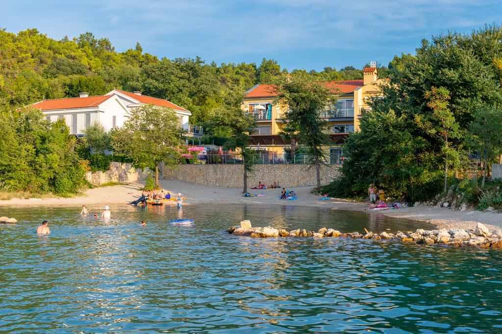 A waterfront property with a swimming area, a beach, and buildings with red roofs.