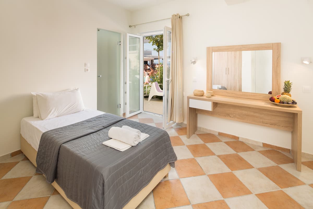 Ein Hotelzimmer mit Bett, Schreibtisch, Spiegel und Blick ins Freie.