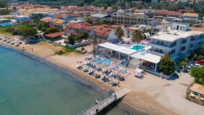 An aerial view of a coastal town with a beach, a pool area, and residential buildings. - Paralia Studios (Corfu)