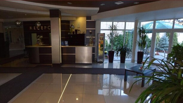 A modern hotel lobby with a reception desk, a glass partition, and a reception area. - Hotel Rydzewski (Elk)