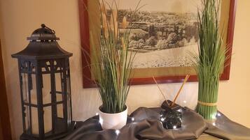 Una mesa con un farol negro, dos plantas en macetas y una pequeña botella.