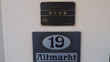Een hotelschilt met een viersterrenbeoordeling en een plaquette met DEHOGA 2025. Daaronder een bord met het nummer 19 en de tekst 'Altmarkt'.
