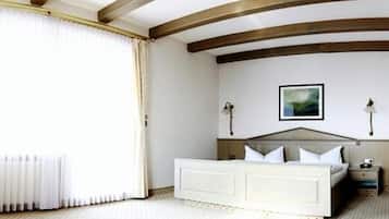 A bedroom with a large bed, a nightstand, a wall-mounted lamp, and a painting.