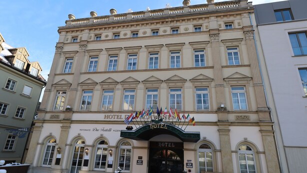 A hotel with a classic facade, multiple windows, and a red carpet entrance.