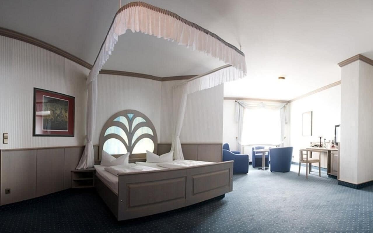 Ein Hotelzimmer mit einem großen Bett, einem Schreibtisch und einem Stuhl.