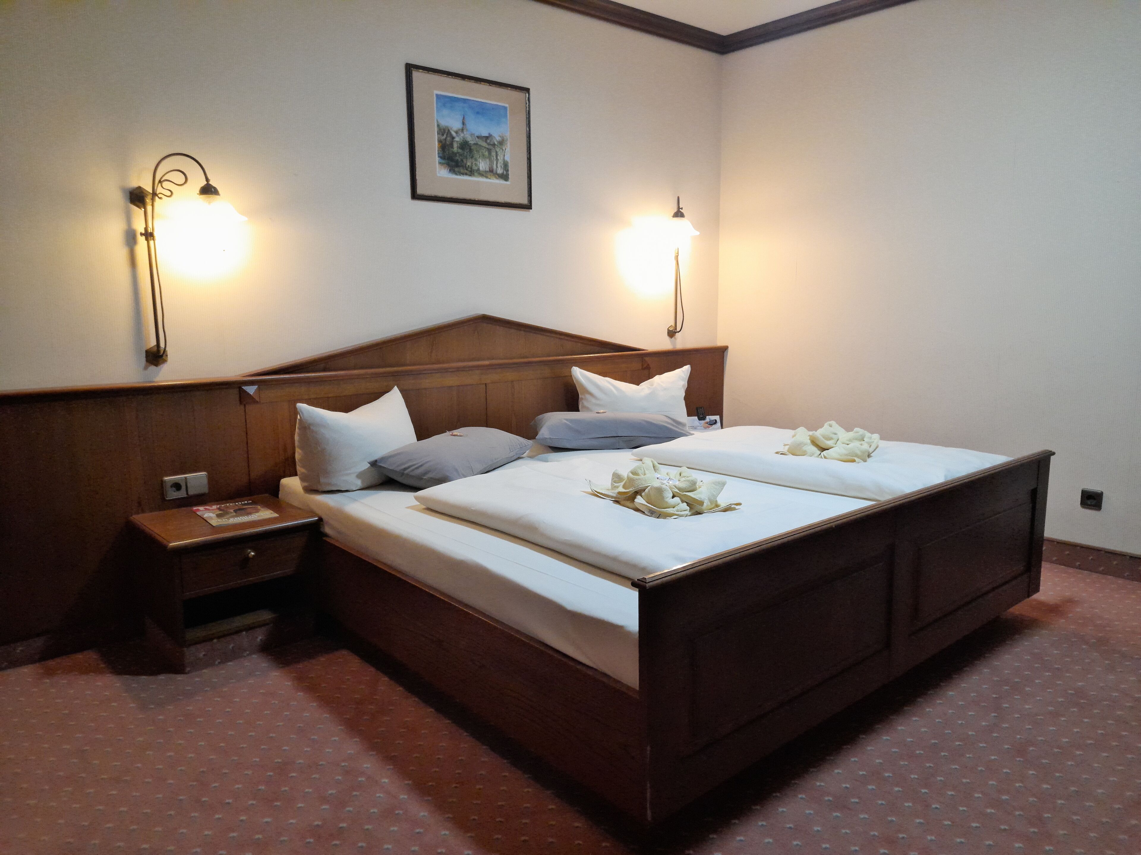 A double bed with a wooden headboard, two bedside tables, and wall-mounted lamps.