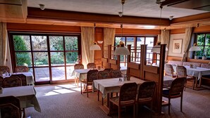 A dining area with tables and chairs, large windows, and a view of the outdoors. - Hotel garni  Zur Weserei (Kandern)