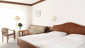 A hotel room with a large bed, a sofa, a desk, and a chair. There is a lamp on the desk and a picture on the wall. - Hotel garni  Zur Weserei (Kandern)