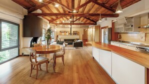 A spacious kitchen with wooden beams, a dining area with a table and chairs, and a cozy living space with a sofa and fireplace. - Telva Alta, country house with tennis in the Dolomites  (Feltre)