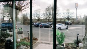 Een parkeerplaats met verschillende auto's en een Shell benzinestation op de achtergrond.