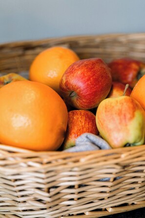 Un panier en osier contenant des pommes et des oranges.