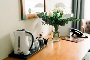 A hotel room with a coffee maker, a vase with white flowers, a phone, and a magazine on the table. - Highway Hotel Dasing – Augsburg (Dasing)
