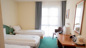 Een hotelkamer met twee enkele bedden, een bureau met stoel, een telefoon en een koffiezetapparaat.