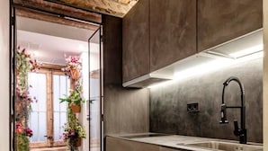 Una cocina moderna con techo de madera, un lavamanos integrado y vistas a una habitación con plantas colgantes.