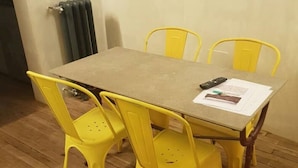 Una mesa de comedor con cuatro sillas amarillas, un control remoto y unos papeles sobre la mesa.