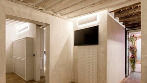 Un interior moderno con techo de madera, televisor de pantalla plana montado en una pared perforada y piso de madera.