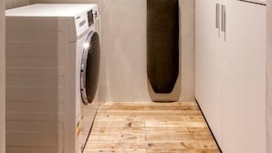 Un lavadero con lavadora, un armario alto y suelo de madera.