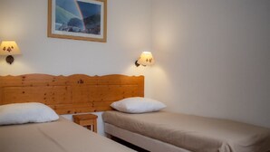A room with two single beds, a wooden headboard, two wall-mounted lamps, and a framed picture on the wall. - Cozy 2-room apartment for 4, mountain view balcony, pets allowed. (Le Dévoluy)