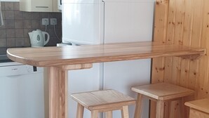 A kitchen with a wooden table, two stools, a microwave, and a Bosch dishwasher. - Semi-detached Chalet 3 Rooms, 6 Pers, Terrace, Parking, Superdevoluy (Le Dévoluy)