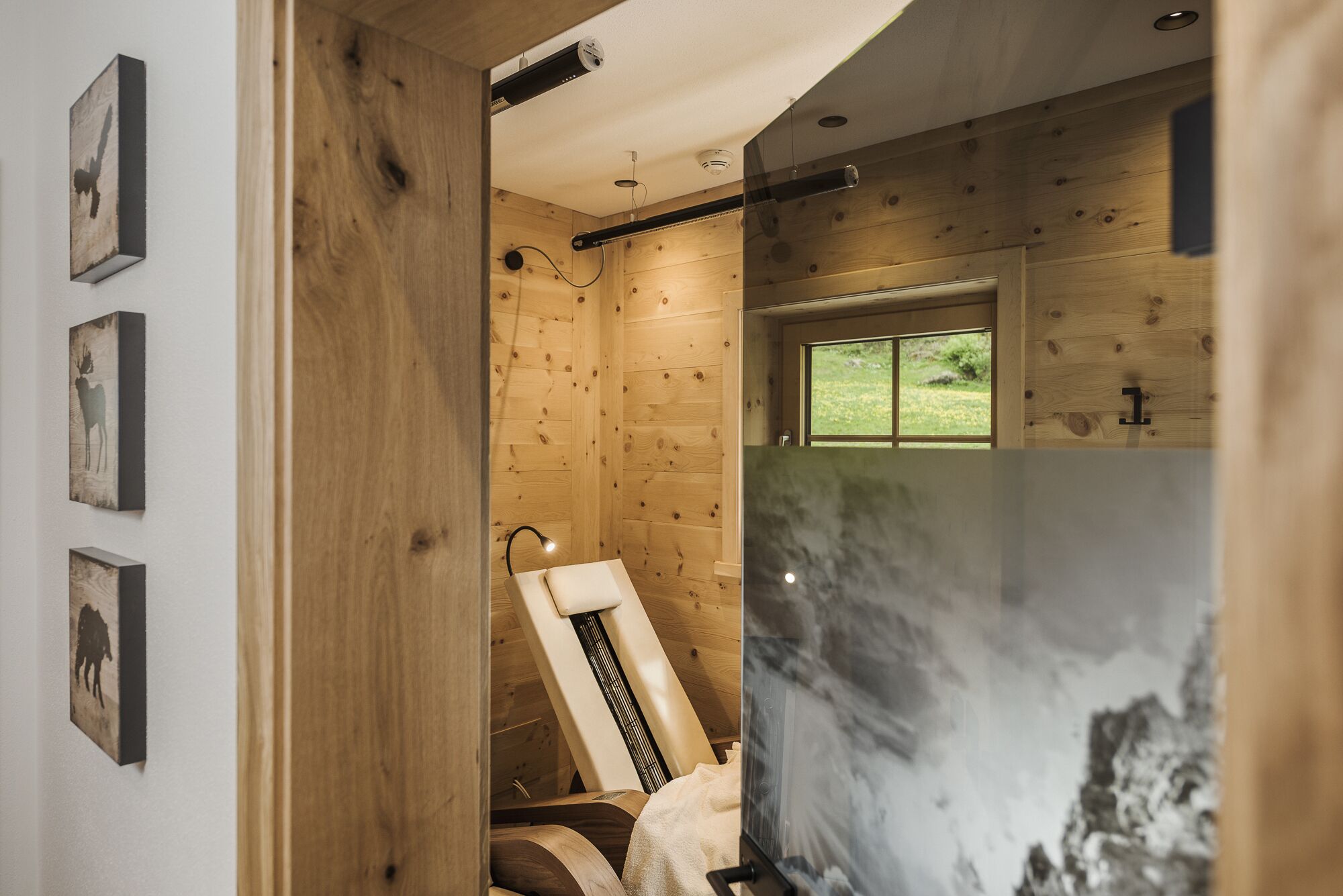 A wooden interior with a shower, a towel rack, and a window with a view of greenery.