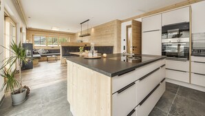 Une cuisine moderne dotée d’un grand îlot central, de meubles en bois et d’appareils électroménagers en acier inoxydable.
