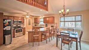 A spacious kitchen with wooden cabinets, a central island, and a dining area with wooden chairs and a table. - 6 Mi to Skiing: Family Poconos Home w Decks! (Albrightsville)