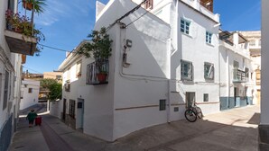 A narrow street with white buildings, a bicycle, and a person with a red bag. - Traditional Spanish casa in the heart of town. (Órgiva)