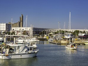 A marina with several boats docked, a building with a tall tower, and a clear blue sky. - Charming 1-Bedroom Apartment with Garden, Terrace, and Parking - Pet Friendly (Vaux-sur-Mer)