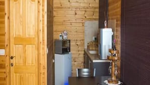 A compact kitchen with wooden walls, a refrigerator, a microwave, and a sink. - Pearl Of The North (Hazor Haglilit)