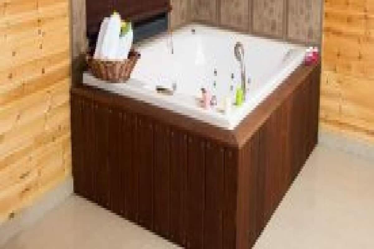 Ein Zimmer mit Holzvertäfelung, einer großen Badewanne, einem Handtuch und Pflegeprodukten.