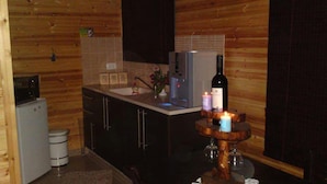 A compact kitchen with a refrigerator, sink, and wooden cabinets. - Pearl Of The North (Hazor Haglilit)