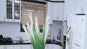 A kitchen with white cabinets, a dining table with chairs, and a decorative plant. - Pearl Of The North (Hazor Haglilit)