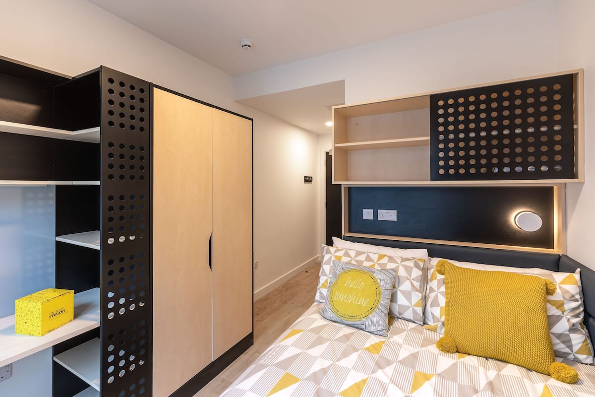 A bedroom with a bed, a wardrobe, and a shelf unit.