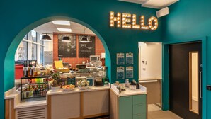 A cafe with a neon 'HELLO' sign, a counter with various food items, and a menu board. - Dominick Place (Dublin)